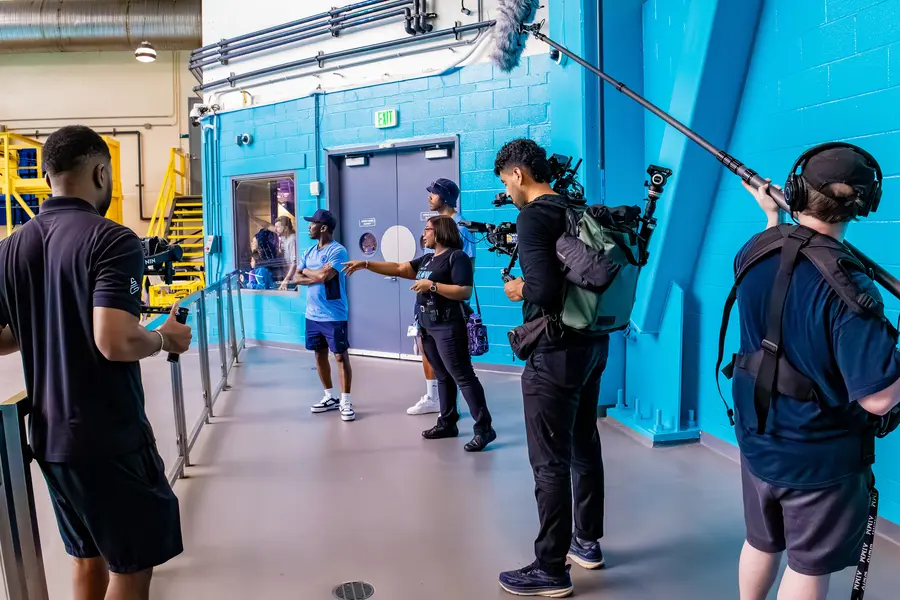 Hylton Media Group production crew on set — blue hallway shoot with camera crew